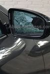 A passenger side door glass mirror on a black car. 
There is is a reflection of the broken glass on the mirror reflecting from the door glass.